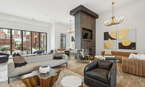 Living room with seating area and a fireplace and floor to ceiling windows in The Ascher apartments in Charlotte.	