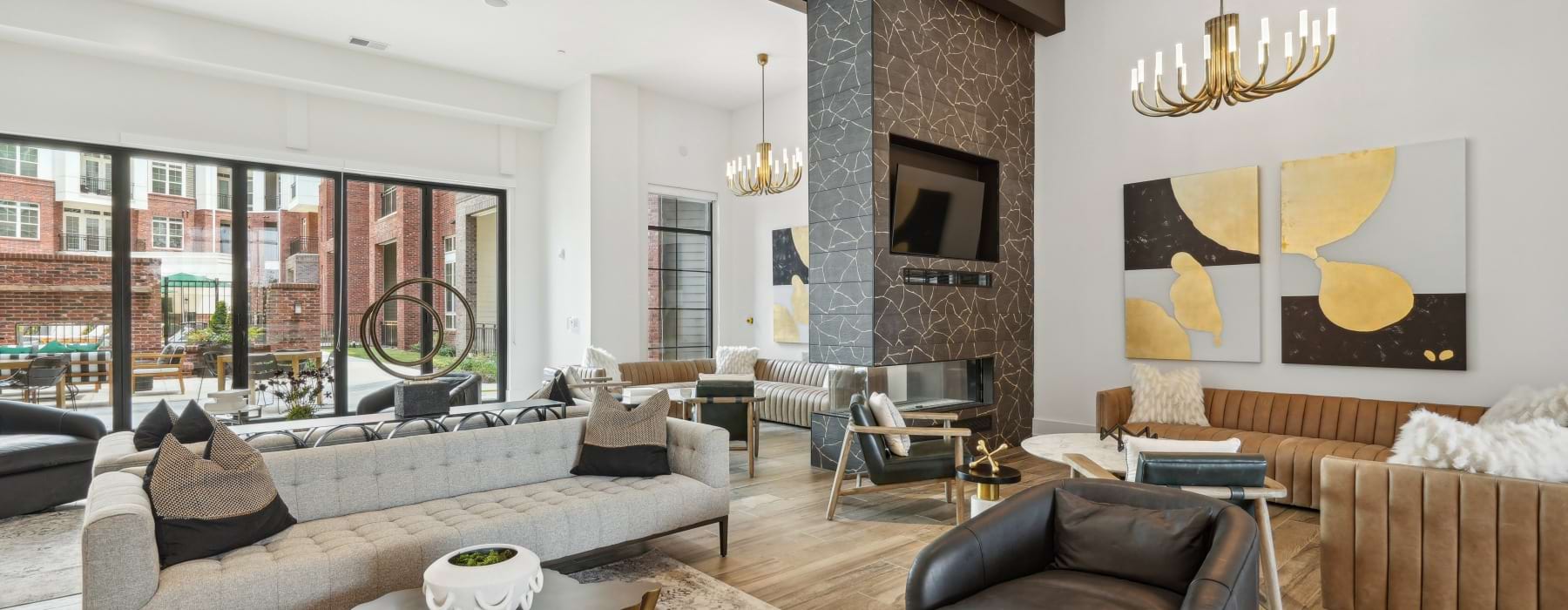 Living room with seating area and a fireplace and floor to ceiling windows in The Ascher apartments in Charlotte.	